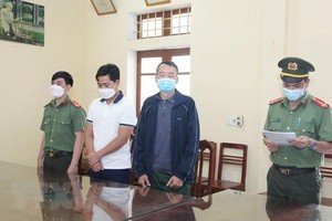 Cơ quan An ninh điều tra đọc lệnh bắt tạm giam đối tượng Khánh và An. (Ảnh: Hoàng Nguyên/TTXVN).