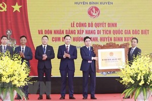 Lãnh đạo huyện Bình Xuyên (bên trái) nhận quyết định và Bằng xếp hạng di tích quốc gia đặc biệt Cụm đình Hương Canh. (Ảnh: Hoàng Hùng/TTXVN).