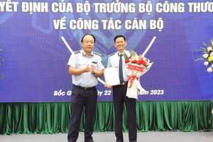Tổng Cục trưởng Tổng Cục QLTT Trần Hữu Linh trao Quyết định và tặng hoa chúc mừng đồng chí Chu Thanh Hiến.