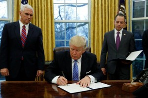  Ông Trump ký sắc lệnhhành pháp (executive order)dưới sự chứng kiến của Phó tổng thống - Mike Pence (trái) và Chánh Văn phòng Nhà Trắng -Reince Priebustại Phòng Bầu dụcngày 23/1 (theo giờ Washington). Ảnh:Reuters