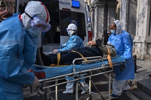 Nhân viên y tế đưa bệnh nhân nghi mắc viêm phổi cấp do virus corona ra khỏi một chung cư tại Vũ Hán, Trung Quốc ngày 30/1. Ảnh: AFP.