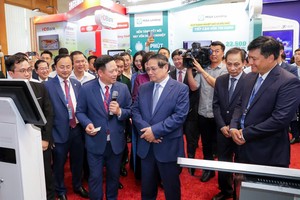 Thủ tướng Chính phủ Phạm Minh Chính thăm và lắng nghe ông Hoàng Minh Ngọc, Phó tổng giám đốc Agribank giới thiệu về hoạt động số của Agribank.