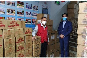 Ông Harry Loh, Tổng giám đốc Ngân hàng UOB Việt Nam (phải) và ông Trần Trường Sơn, Chủ tịch Hội Chữ thập đỏ TP.HCM (trái) cùng với số lượng đồ hộp và vật tư y tế sẵn sàng để phân phối