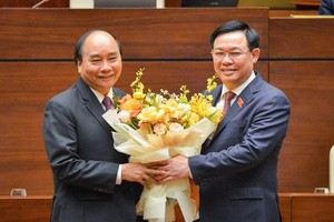 Thủ tướng Nguyễn Xuân Phúc (trái) nhận hoa chúc mừng của Chủ tịch Quốc hội Vương Đình Huệ (Ảnh Quochoi.vn).