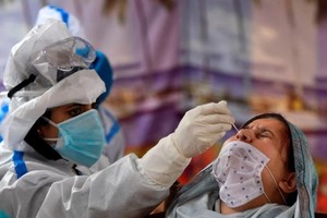 Nhân viên y tế lấy mẫu xét nghiệm tại một trung tâm xét nghiệm Covid-19 ở thành phố Srinagar, Ấn Độ. Ảnh: AFP