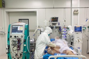Bác sĩ bệnh viện Chợ Rẫy khám cho bệnh nhân H.C.C khi còn nguy kịch, phải chạy ECMO nhưng từ ngày 6/7, bệnh nhân đã tỉnh táo hơn. Dù bệnh nhân vẫn còn phải thở oxy dòng cao do phổi còn hạn chế vì thể trạng béo phì, tuy nhiên tình trạng sức khỏe đang cải thiện dần (Ảnh: Bệnh viện Chợ Rẫy).