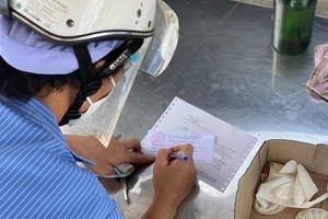 Người dân tại TP.HCM điền thông tin vào thẻ ra vào chợ Bà Chiểu, quận Bình Thạnh (Ảnh: Q.T).