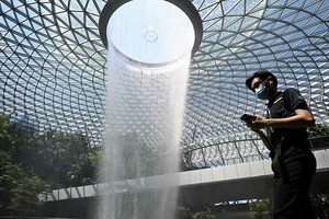 Hành khách di chuyển qua khu vực thác nước Rain Vortex tại sân bay Jewel Changi, Singapore ngày 27/2/2020. Ảnh tư liệu: AFP