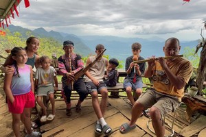Giàng A La hướng dẫn du khách nước ngoài sử dụng nhạc cụ truyền thống của đồng bào Mông.