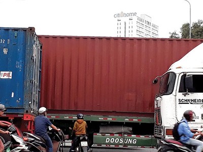 Bị xe container bịt kín lối đi, người dân phải luồn lách trước bánh xe “hung thần” để về nhà. Ảnh: Việt Dũng