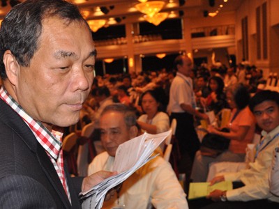 Ông Trầm Bê đi thu phiếu biểu quyết của cổ đông tại Đại hội cổ đông Sacombank tháng 7/2015, bàn về sáp nhập với Ngân hàng Phương Nam.. Ảnh: Lệ Chi