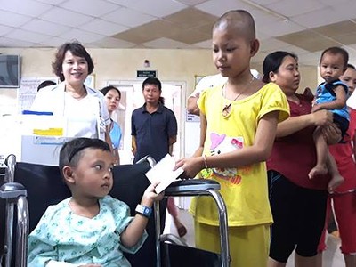 Em Tiến (ngồi xe lăn) trao quà hỗ trợ cho các bệnh nhi nghèo. Ảnh: X.D.