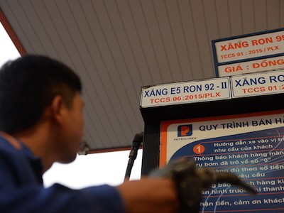 Nhân viên cây xăng tại TP HCM xem bảng giá trước khi bơm xăng cho khách. Ảnh: Hữu Khoa.