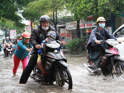 Một gia đình TP HCM đưa con đi học trong cơn mưa ở TP HCM. Ảnh minh họa: Mạnh Tùng.