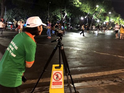 Nhân viên công ty môi trường ghi hình người xả rác bừa bãi ở phố đi bộ Hồ Gươm. Ảnh: N.H.