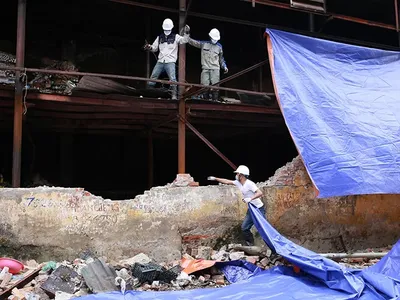 Công nhân quây bạt che kín khu vực hiện trường vụ cháy, hạn chế ảnh hưởng ra xung quanh. Ảnh: Tất Định.