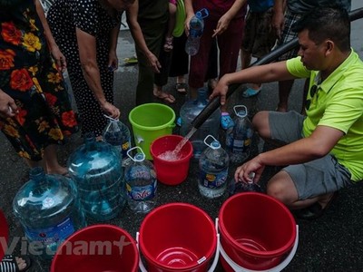 Người dân xếp hàng lấy nước sạch. (Ảnh: PV/Vietnam+).