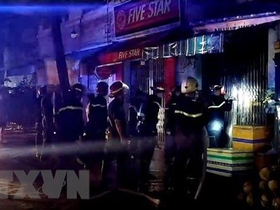 Cảnh sát phòng cháy chữa cháy phá cửa để cứu hộ. (Ảnh: TTXVN)