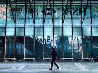 Một người đeo khẩu trang đi bộ trước Ngân hàng HSBC tại Hong Kong. Ảnh: CNN.