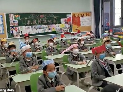 Bằng cách đội mũ giãn cách một mét, cách em học sinh tiểu học sẽ hạn chế tiếp xúc gần nhau.  