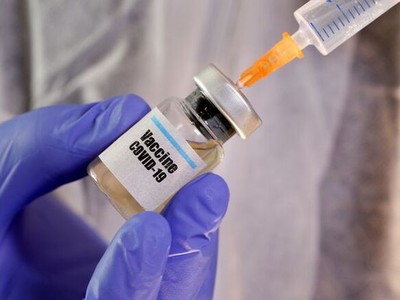 Một phụ nữ cầm lọ dán nhãn vaccine Covid-19 và ống tiêm trong hình ảnh minh hoạ được chụp hôm 10/4. Ảnh: Reuters.