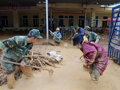 Bộ đội giúp địa phương xã Hướng Việt thu dọn bùn đất tại trường học. (Ảnh: Hồ Cầu/TTXVN).