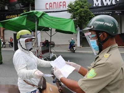 Một người phụ nữ đi chợ trình giấy có giấy tiêm đủ vaccine cho lực lượng kiểm tra trên đường Yersin, thành phố Thủ Dầu Một. (Ảnh: Chí Tưởng/TTXVN).