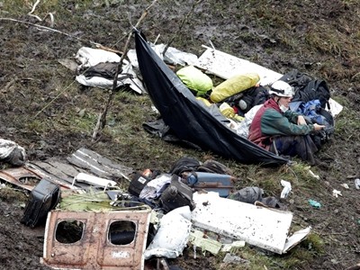 Nhân viên cứu hộ ngồi bên các mảnh vỡ của máy bay. Ảnh: Reuters