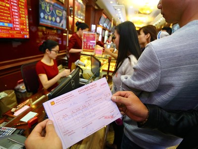Khách hàng cầm trên tay giấy hẹn lấy vàng ngày vía Thần Tài tại một cửa hiệu vàng trên phố Trần Nhân Tông