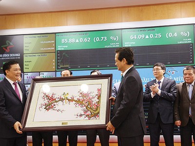 Bộ trưởng Bộ Tài chính Đinh Tiến Dũng nhận quà lưu niệm từ Thủ tướng Chính phủ nhân sự kiện Thủ tướng đến đánh cồng phiên giao dịch đầu Xuân Ất Mùi tại HNX, tháng 2/2015