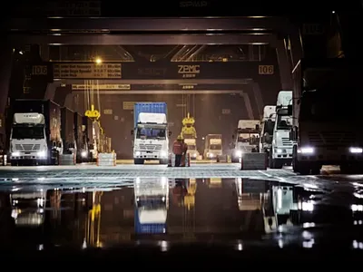 Xe tải chờ nhận hàng ban đêm tại một cảng ở Hạ Môn, Trung Quốc. Ảnh: Bloomberg