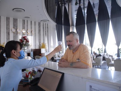 Nhân viên một khách sạn tại Khánh Hòa kiểm tra thân nhiệt cho du khách tại quầy đón tiếp