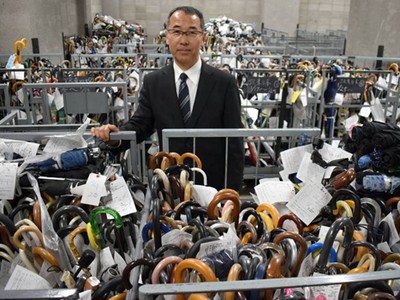 Ông Shoji Okubo, giám đốc trung tâm xử lý đồ thất lạc của Sở cảnh sát Tokyo, đứng giữa những chiếc ô vô chủ. Ảnh: Japan Times 