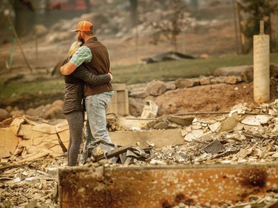 Cặp vợ chồng ôm nhau giữa ngôi nhà đã bị ngọn lửa thiêu hủy hoàn toàn tại thị trấn Paradise hôm 12/11. Ảnh: AP.