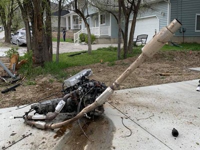 Động cơ và ống xả bay khỏi xe, nằm trên lối đi của một ngôi nhà ven đường.