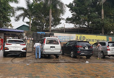 Tiệm rửa xe báo giá 200.000 đồng một lần rửa ôtô, song vẫn kín khách với nhiều người ngồi chờ trong sáng ngày 29 Tết. Ảnh: Minh Châu