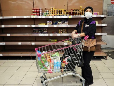 Một phụ nữ đeo khẩu trang mua đồ trong một siêu thị ở Kuala Lumpur. Ảnh: Reuters.