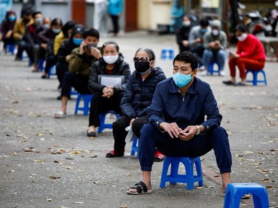 Người dân ngồi cách xa nhau trong khi chờ đến lượt tại một cơ sở xét nghiệm nhanh ở Hà Nội. Ảnh: Reuters.
