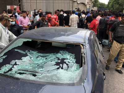 Đám đông tụ tập gần một chiếc xe bị bắn vỡ cửa kính tại lối vào sở giao dịch chứng khoán ở Karachi, Pakistan hôm nay. Ảnh: Reuters.
