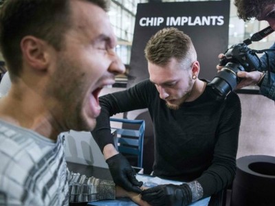 Một người đàn ông đang nhịn đau để cấy chip dưới da tay. Ảnh: AFP.