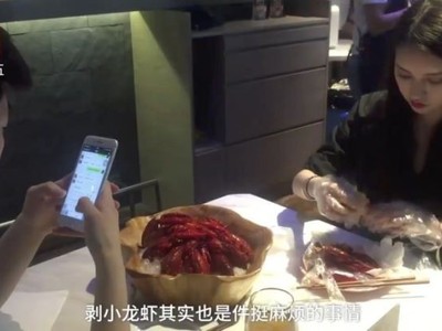 Nhân viên ngồi bóc vỏ tôm càng trong khi thực khách dùng điện thoại di động. (Nguồn: Handout)