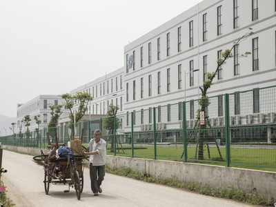 Một người đàn ông đang kéo một chiếc xe kéo phía trước nhà máy được điều hành bởi Tập đoàn Công nghệ Quang học Sunny. (Nguồn: Qilai Shen/Bloomberg).