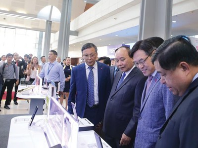Thủ tướng Chính phủ Nguyễn Xuân Phúc (thứ ba, từ phải qua), Bộ trưởng Bộ Kế hoạch và Đầu tư Nguyễn Chí Dũng (ngoài cùng, bên phải) thăm gian hàng của Sam sung tại triển lãm tổ chức nhân Hội nghị 30 năm thu hút FDI.