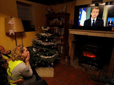 Người biểu tình “Áo ghi-lê vàng” nghe bài phát biểu của Tổng thống Pháp Emmanuel Macron trên truyền hình tại Gaillon hôm 10-12 Ảnh: REUTERS.