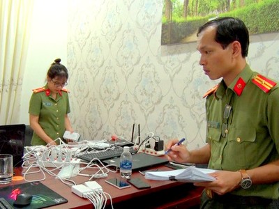 Công an kiểm đếm thiết bị điện tử tại nơi nhóm người Trung Quốc thuê để làm thẻ ATM giả và đánh bạc. Ảnh: Quang Bình. 