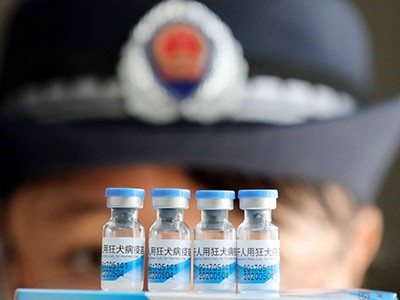 Cán bộ hành pháp Trung Quốc đưa một lô vắcxin đi kiểm tra. Ảnh: EPA.