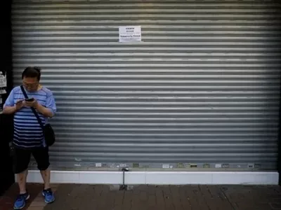 Một người qua đường đứng trước cửa tiệm dán thông báo đóng cửa vì biểu tình ở Hong Kong hôm 5/8. Ảnh: Reuters.