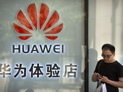 Một người đang sử dụng điện thoại bên ngoài cửa hàng Huawei ở Bắc Kinh. (Nguồn: AP)