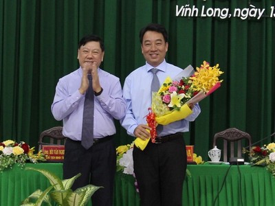 Ông Trần Văn Rón, Ủy viên Trung ương Đảng, Bí thư Tỉnh ủy Vĩnh Long (bên trái) tặng hoa chúc mừng tân Chủ tịch UBND tỉnh Vĩnh Long Lữ Quang Ngời.