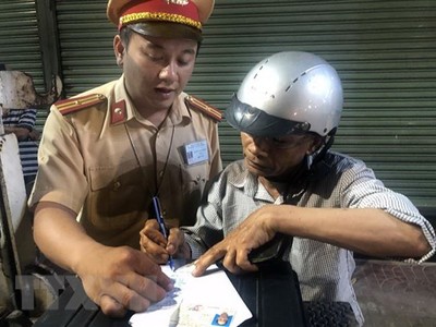 Lái xe môtô vi phạm nồng độ cồn ký biên bản vi phạm hành chính. (Ảnh: Nguyên Linh/TTXVN).